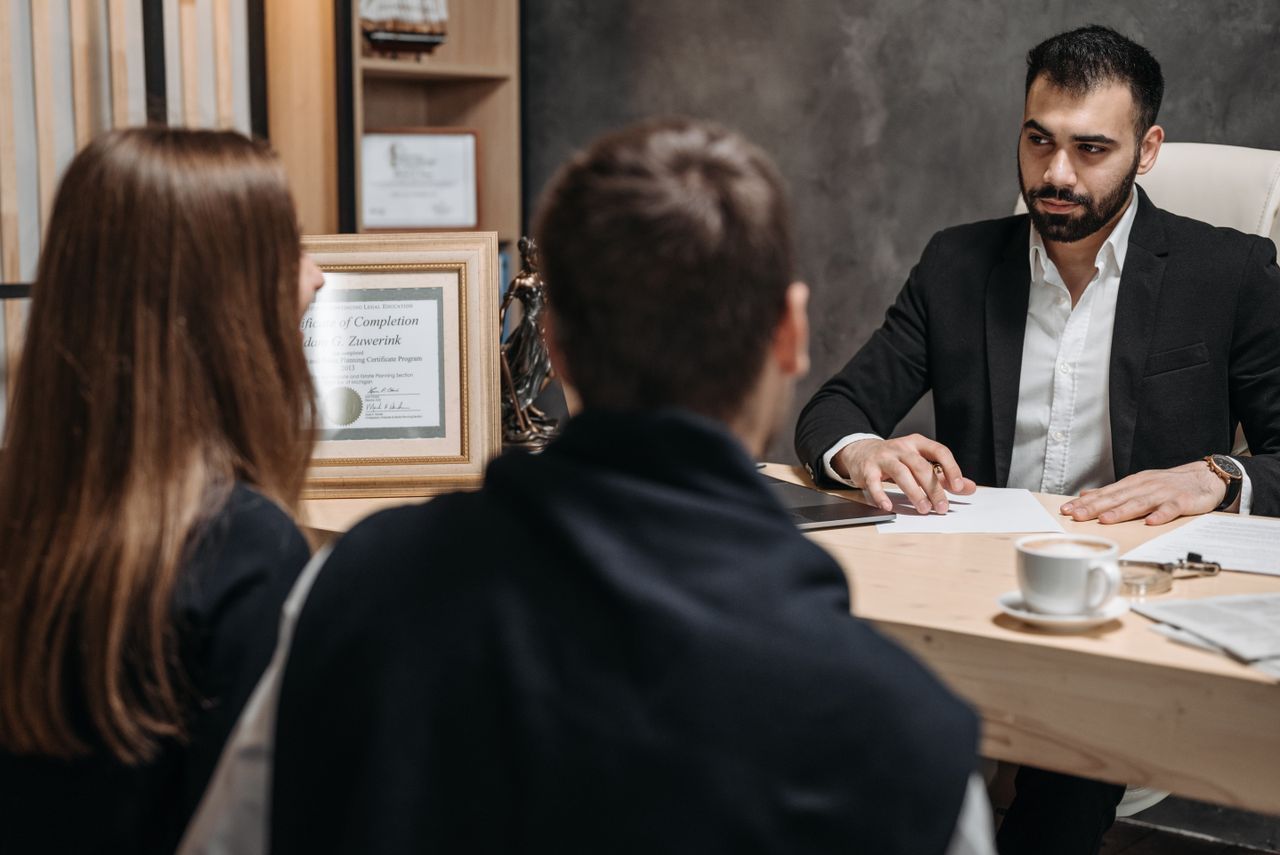 Services A lawyer in an elegant office meeting with clients, discussing documents.